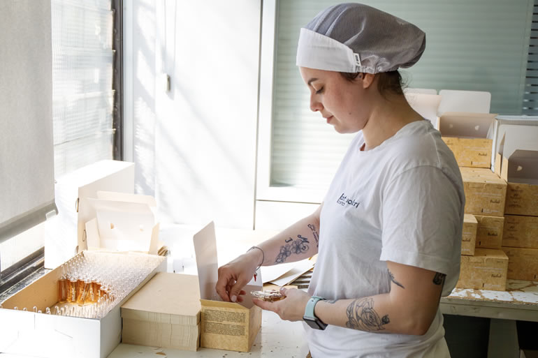 Сотрудница Dott Solari Dana упаковывает продукцию. Женщина в рабочей одежде за столом с коробками. Персонал компании.